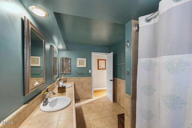 full bath featuring a sink, tile walls, a shower with shower curtain, and tile patterned floors