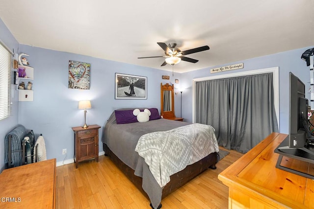 bedroom with light wood-style floors, baseboards, and a ceiling fan