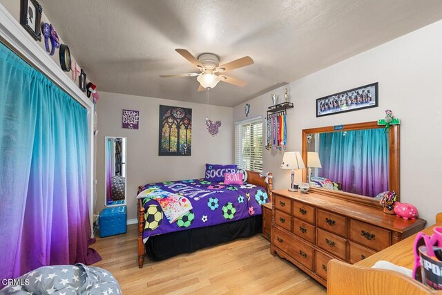 bedroom with a textured ceiling, light wood-type flooring, and a ceiling fan