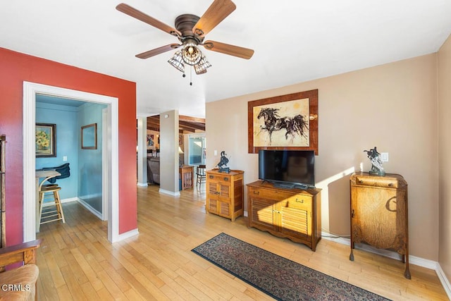 interior space with light wood-type flooring, a ceiling fan, and baseboards