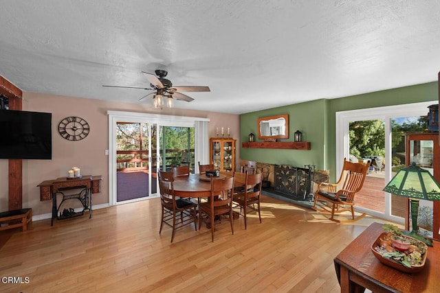 dining space with plenty of natural light, a textured ceiling, and light wood finished floors