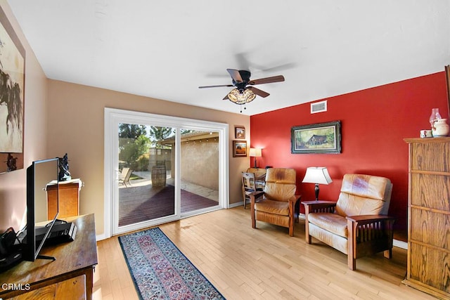 sitting room with light wood-type flooring, baseboards, visible vents, and a ceiling fan