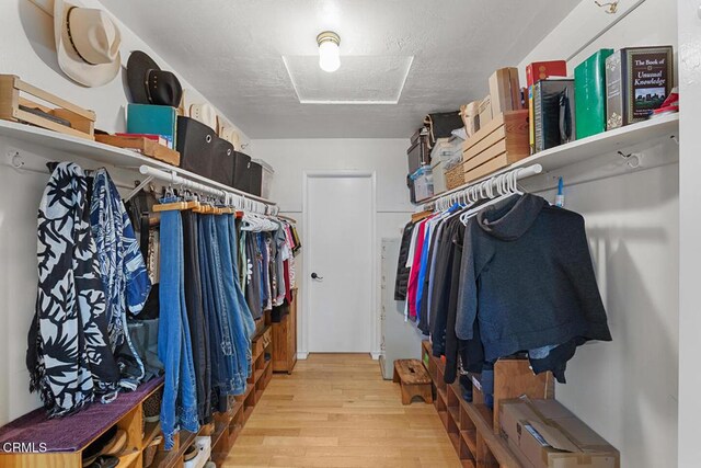 walk in closet featuring light wood finished floors and attic access