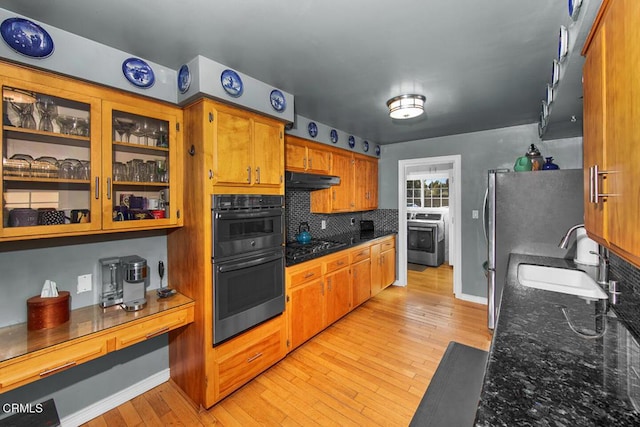 kitchen with tasteful backsplash, washer / clothes dryer, multiple ovens, brown cabinetry, and a sink