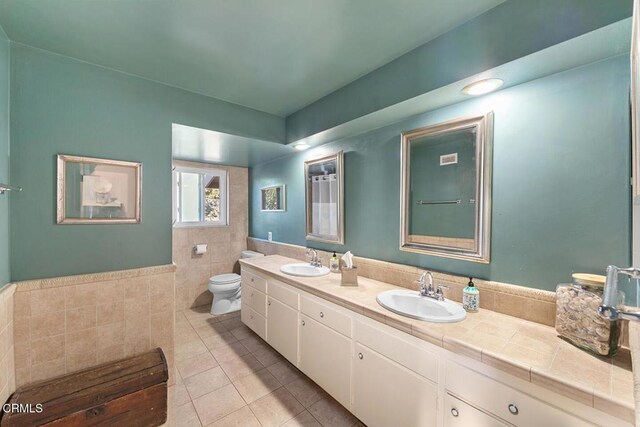 bathroom featuring a sink, tile walls, toilet, and tile patterned floors