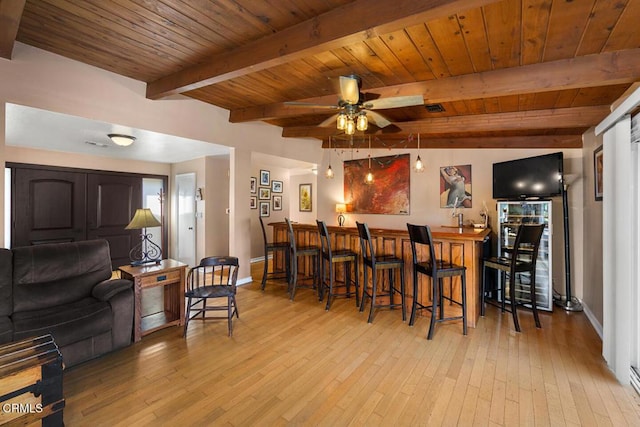 interior space with light wood-style flooring, bar, wood ceiling, baseboards, and beam ceiling