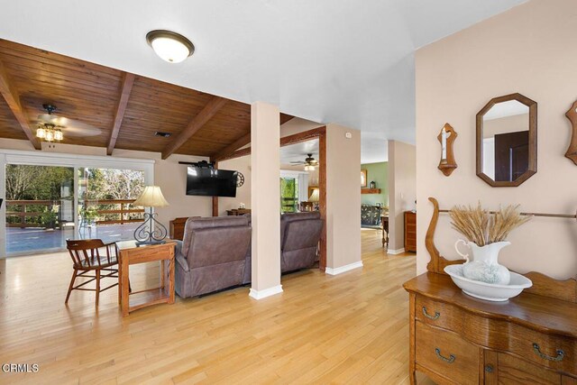 living area featuring light wood finished floors, lofted ceiling with beams, a ceiling fan, wooden ceiling, and baseboards