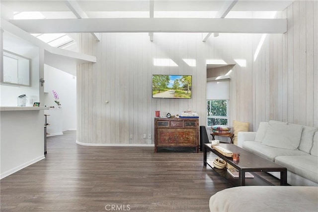 living area featuring beamed ceiling, wood finished floors, baseboards, and wood walls