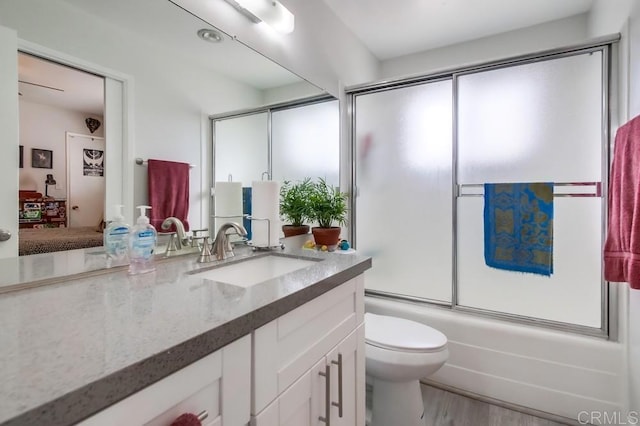 full bathroom with vanity, hardwood / wood-style flooring, toilet, and enclosed tub / shower combo