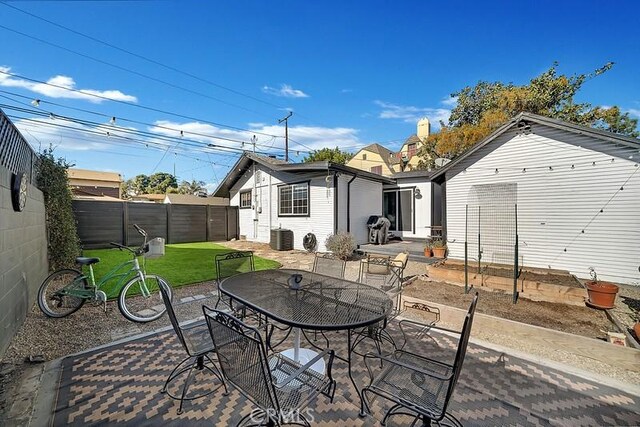 rear view of property with central air condition unit, a patio area, and a lawn