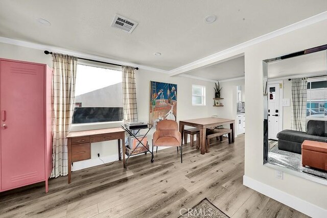 interior space featuring plenty of natural light, light wood-type flooring, and ornamental molding