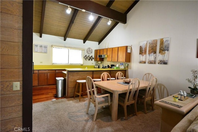 dining area featuring hardwood / wood-style floors, wooden ceiling, high vaulted ceiling, rail lighting, and beam ceiling