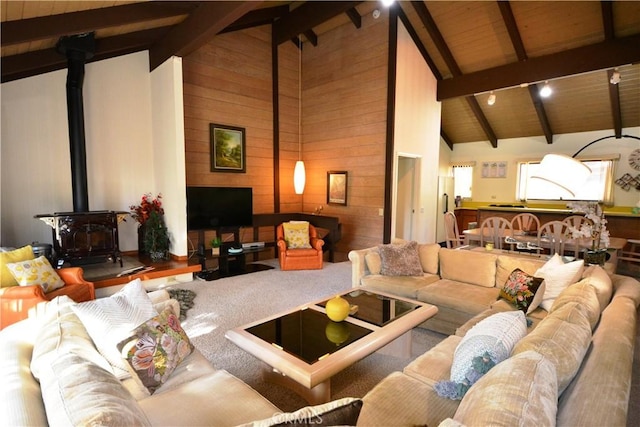 living room with beam ceiling, a wood stove, and wood walls