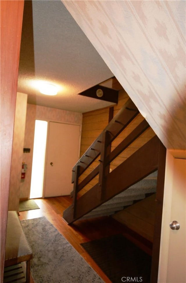 stairs featuring wood walls and hardwood / wood-style flooring