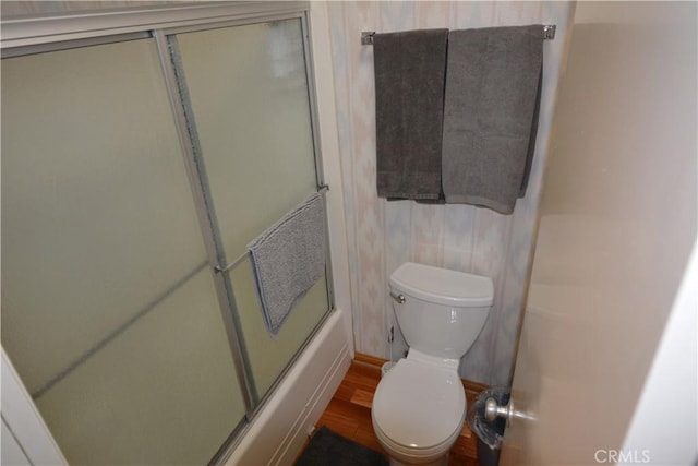 bathroom featuring shower / bath combination with glass door, wood-type flooring, and toilet