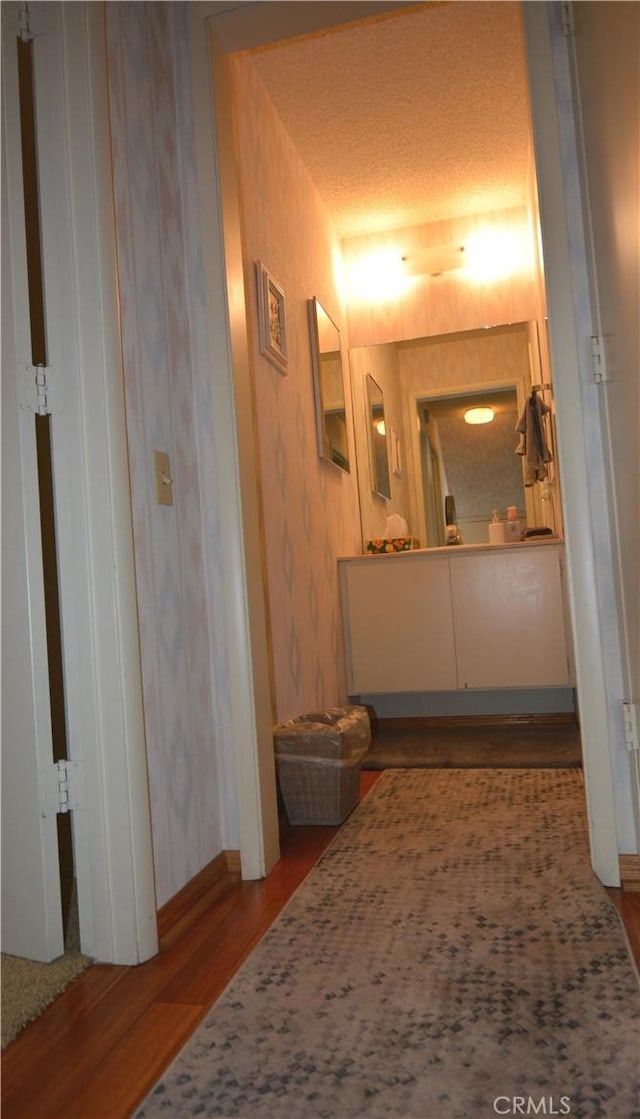 hallway with a textured ceiling and hardwood / wood-style flooring