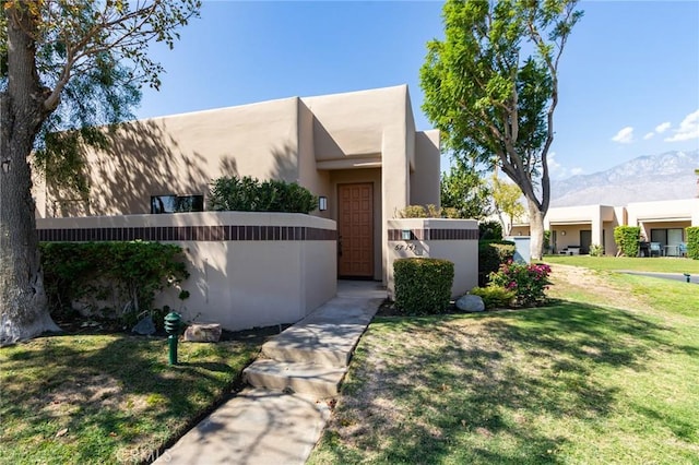 southwest-style home with a mountain view, a front lawn, and central AC unit