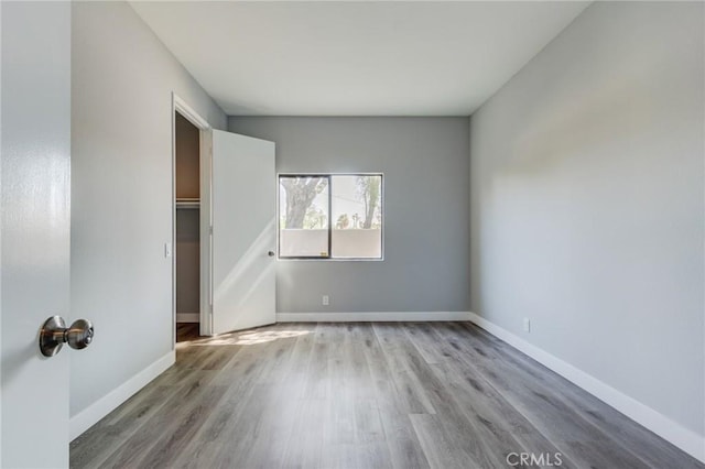 unfurnished bedroom with a spacious closet, light wood-type flooring, and a closet