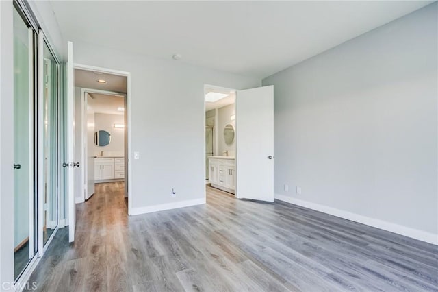 unfurnished bedroom with light wood-type flooring, a closet, and connected bathroom