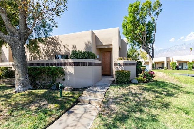 view of front of house with a mountain view and a front lawn