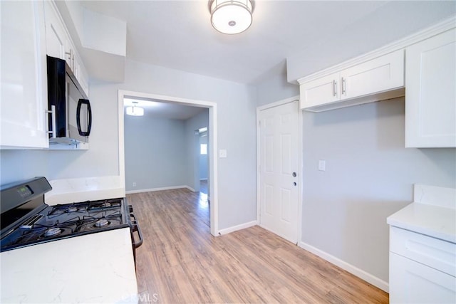 kitchen with white cabinetry, light hardwood / wood-style flooring, and white gas range