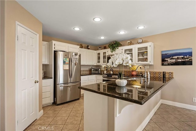 kitchen with kitchen peninsula, appliances with stainless steel finishes, sink, and white cabinetry