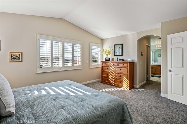 carpeted bedroom with connected bathroom and vaulted ceiling