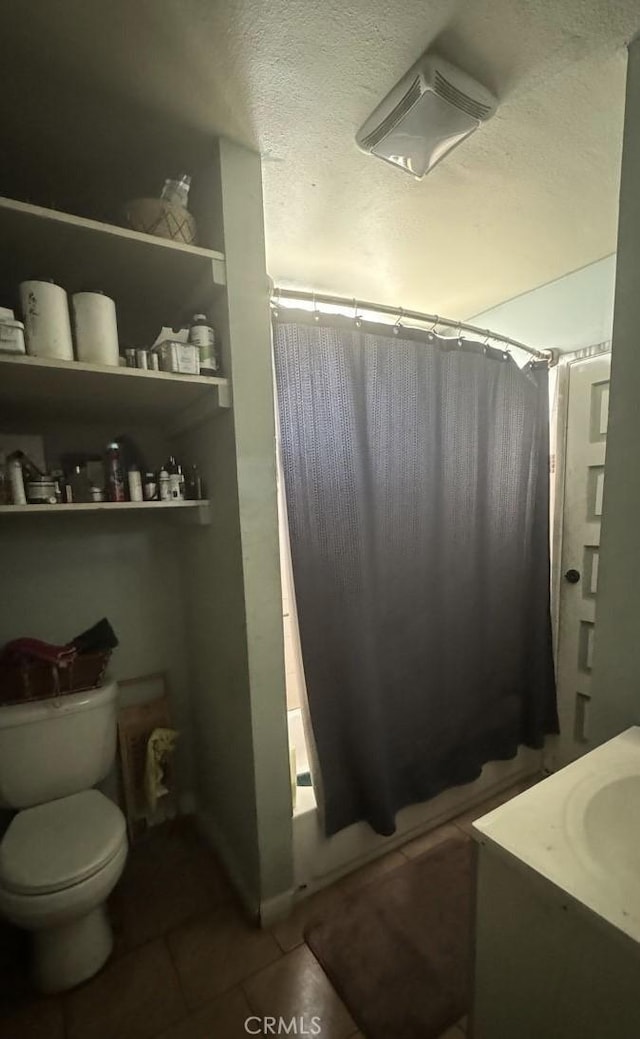 full bathroom featuring vanity, tile patterned flooring, toilet, shower / bath combo with shower curtain, and a textured ceiling