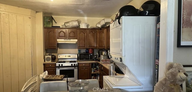 kitchen featuring stacked washer / dryer, dark brown cabinetry, stainless steel appliances, and a textured ceiling