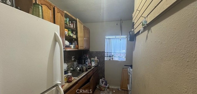 kitchen featuring decorative backsplash, white refrigerator, and sink