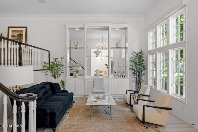 sitting room with light hardwood / wood-style floors, crown molding, and an inviting chandelier