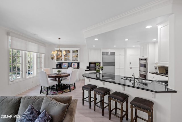 kitchen with pendant lighting, light hardwood / wood-style floors, white cabinetry, and appliances with stainless steel finishes