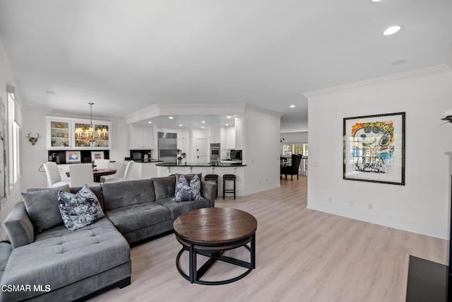 living room featuring light hardwood / wood-style flooring, ornamental molding, and an inviting chandelier