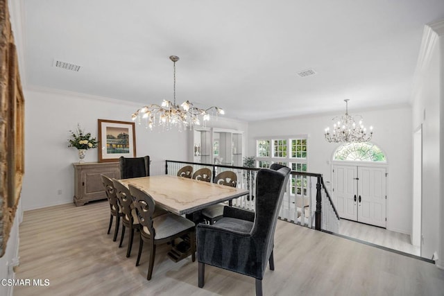 dining room featuring ornamental molding, light hardwood / wood-style flooring, and a chandelier