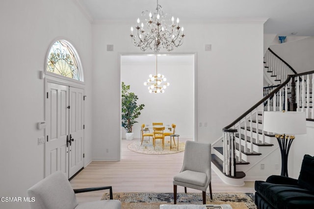 foyer featuring a chandelier, a towering ceiling, light hardwood / wood-style floors, and crown molding