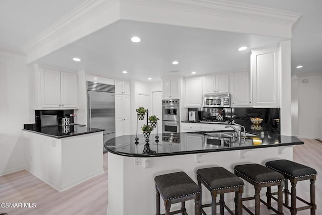 kitchen with kitchen peninsula, appliances with stainless steel finishes, white cabinets, and sink