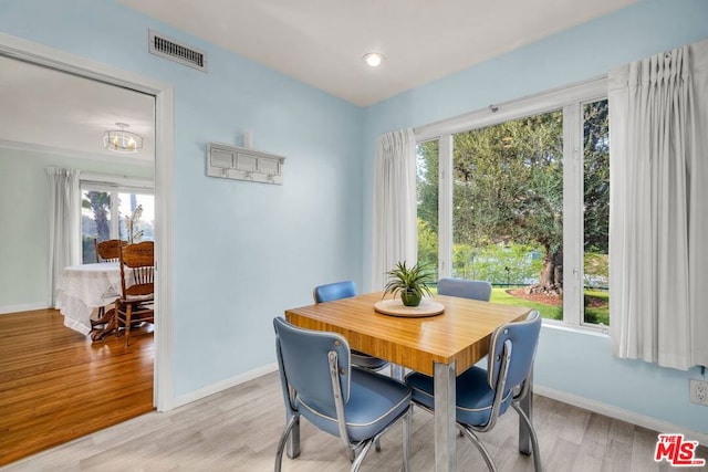 dining room with light hardwood / wood-style flooring and a healthy amount of sunlight