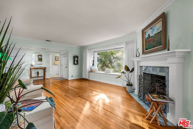 living room with a tiled fireplace, crown molding, and hardwood / wood-style flooring