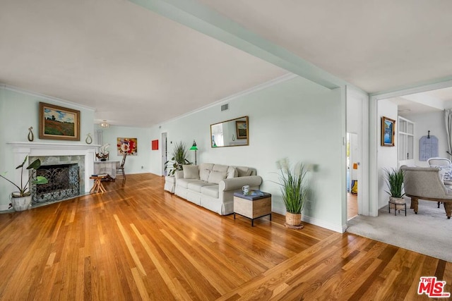 living room featuring hardwood / wood-style flooring, ornamental molding, and a high end fireplace