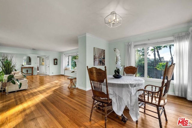 dining space featuring ornamental molding, wood-type flooring, and an inviting chandelier