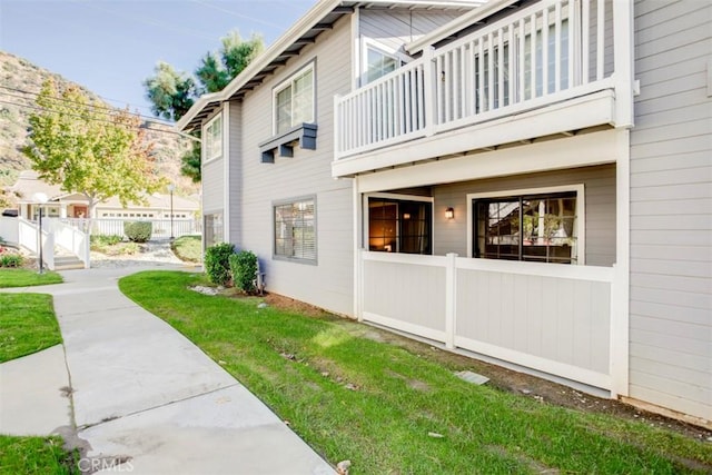 view of property exterior featuring a balcony and a lawn