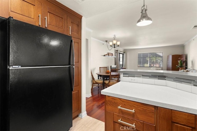 kitchen featuring a notable chandelier, black refrigerator, decorative light fixtures, and light hardwood / wood-style flooring