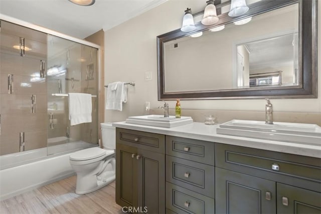 full bathroom with combined bath / shower with glass door, vanity, hardwood / wood-style flooring, and toilet