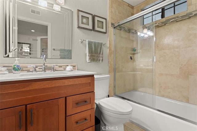 full bathroom featuring toilet, combined bath / shower with glass door, and vanity