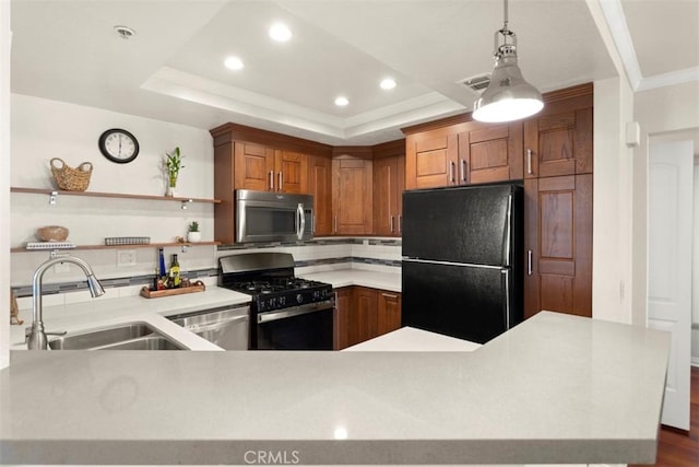 kitchen with pendant lighting, sink, appliances with stainless steel finishes, a tray ceiling, and kitchen peninsula