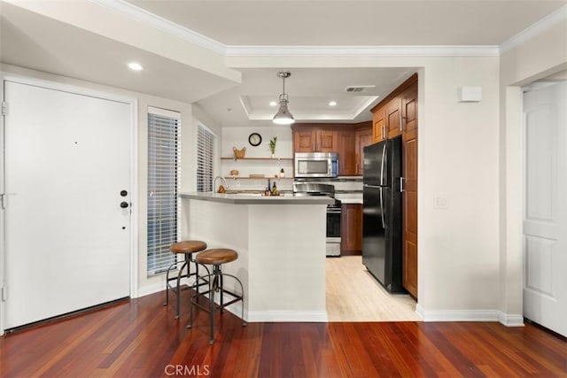 kitchen featuring a breakfast bar, appliances with stainless steel finishes, kitchen peninsula, and light hardwood / wood-style flooring