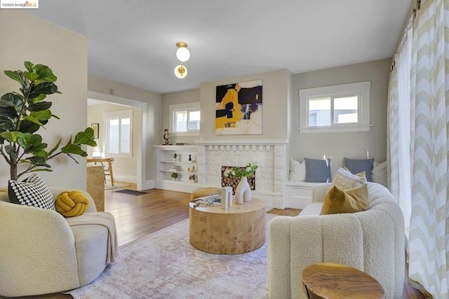 living room featuring hardwood / wood-style floors, a healthy amount of sunlight, and a brick fireplace