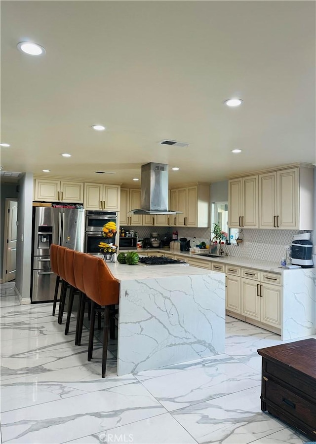 kitchen with a breakfast bar, decorative backsplash, appliances with stainless steel finishes, range hood, and a kitchen island