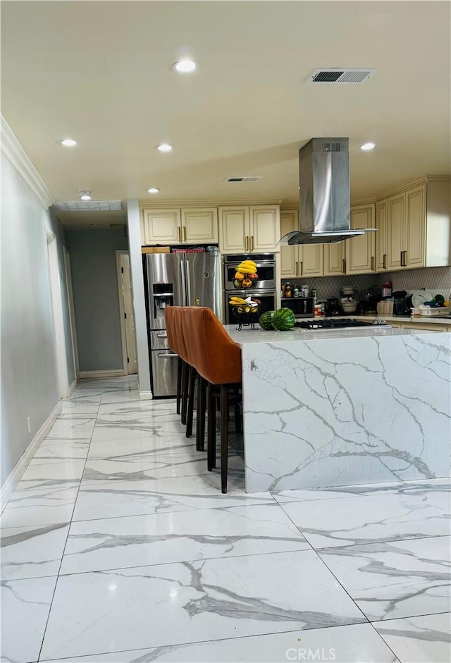 kitchen with island exhaust hood, tasteful backsplash, ornamental molding, stainless steel appliances, and a breakfast bar area