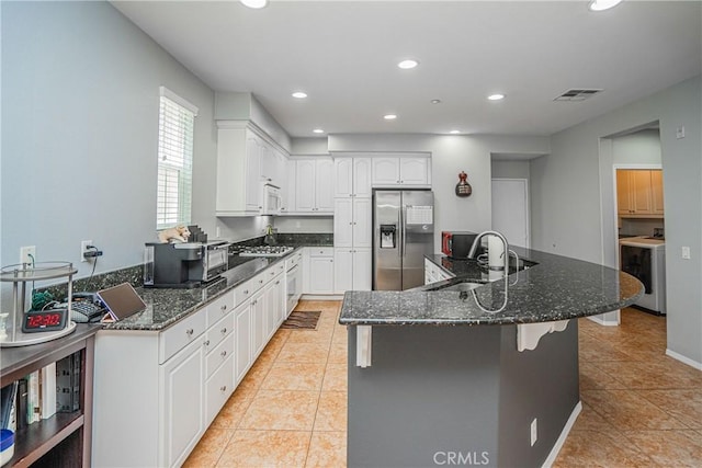 kitchen with sink, white cabinetry, stainless steel appliances, and dark stone counters